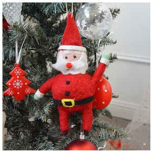 Close-up of a red wool felt Santa Claus ornament hanging on a green Christmas tree branch