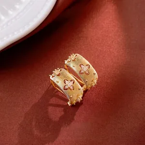 Luxury gold plated four-leaf clover stud earrings with white zircon on velvet background
