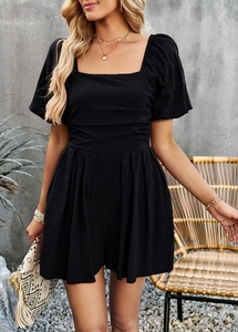 Detail of elegant black romper with square neckline and pleated shorts on a model