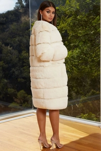 Detail of cream faux fur coat featuring a layered horizontal panel design and fluffy texture