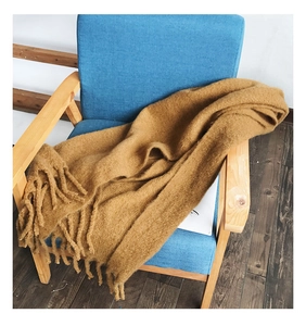 Close-up of soft mustard yellow cashmere-like scarf with chunky tassels on an armchair