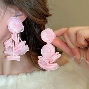 Detail of pink fabric flower earrings with beaded centers on a model