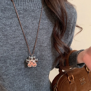Detailed macro view of cat paw pendant with pink leopard print on grey sweater