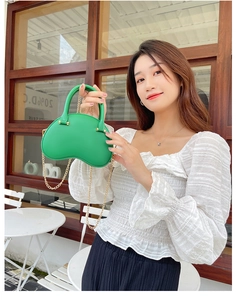 Detail of green PVC jelly bag featuring a curved design and golden chain shoulder strap