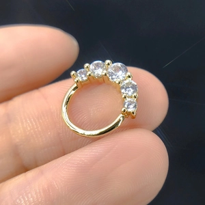 Macro shot of gold septum ring with five clear micro-pave zircons held between fingers