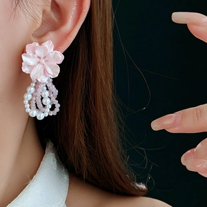 Detail of pink flower beaded earrings with layered faux pearls worn by a model