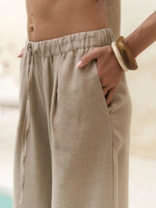 Detailed view of women's beige linen wide-leg pants featuring a drawstring elastic waist
