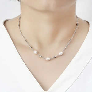 Detail of elegant pearl necklace with three white pearls on a silver beaded chain