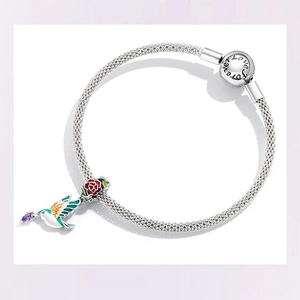 Detail of silver mesh bracelet with Forever Love clasp, rose charm and colorful hummingbird