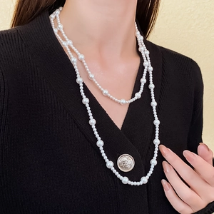 Close-up of double-layered long pearl necklace worn on a black V-neck cardigan