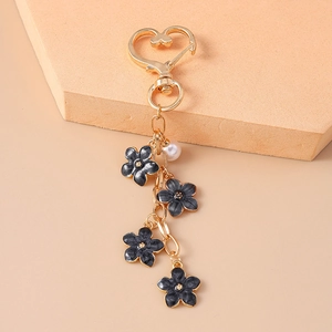 Detailed shot of black enamel flowers and white pearl bead on golden keychain