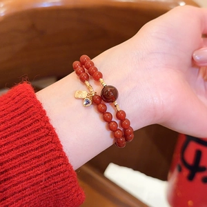 Detailansicht eines roten Karneol-Armbands mit goldenem Fu-Anhänger und Herzanhänger