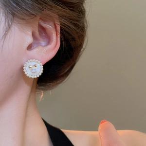 Gros plan de boucles d'oreilles fleur en perles avec nœud doré portées par un mannequin