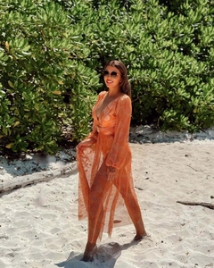 Detail of orange mesh beach cover-up with long sleeves and floral print swimsuit