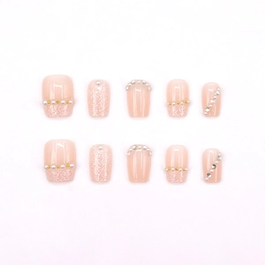 Elegant nude pink press-on nails with pearls, gold beads, and glitter french tips