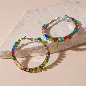 Detail of silver hoop earrings with multicolored rainbow crystal beads on stone