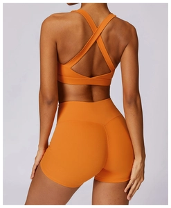 Detail view of the criss-cross back sports bra and high-waisted orange gym shorts