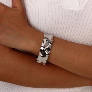 Detail of silver wavy hammered metal cuff bracelet worn on model with white knit top