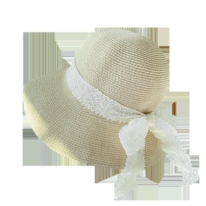 Detail of summer straw hat featuring delicate floral lace ribbon and elegant bow accent
