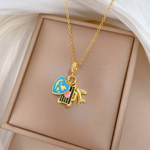 Close-up of gold airplane, suitcase, and blue heart charms on a luxury necklace