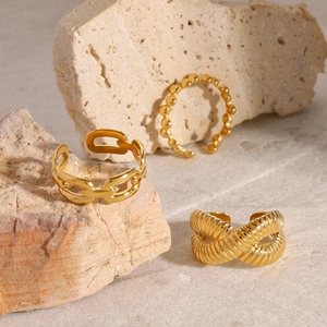 Set di tre anelli dorati con texture a catena e intrecciata su pietra naturale chiara