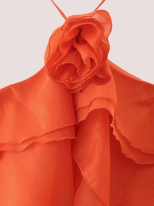 Détail de la robe orange à volants avec une grande fleur 3D et un col licou froncé