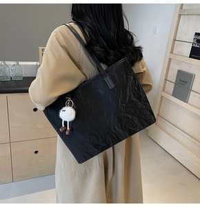 Grande borsa tote nera con trama stropicciata e ciondolo di peluche bianco sulla spalla