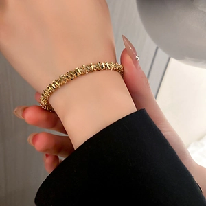 Close-up of golden geometric block link bracelet with high polished metallic texture