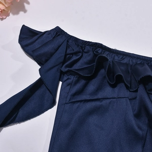 Dettaglio dell'abito blu navy con spalle scoperte, volant e tessuto lucido