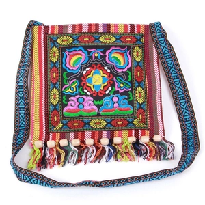Detail of ethnic embroidery pattern with colorful tassels and wooden beads on canvas bag