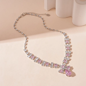 Macro view of luxurious zircon bow necklace with pink pear-shaped droplet gemstone