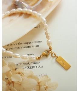 Detailed macro shot of freshwater pearl bracelet with a gold engraved Love pendant charm