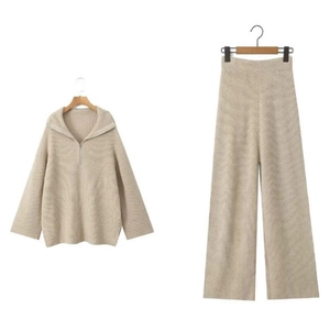 Détail de l'ensemble en tricot beige avec pull à demi-zip et pantalon large sur fond blanc