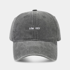 Detailed view of the LOW KEY white embroidery on a washed dark gray cotton baseball cap