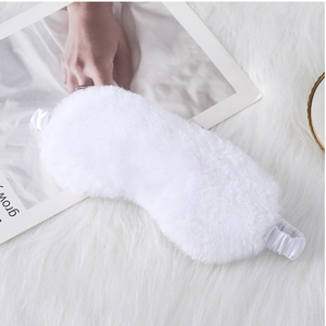 Detail of white faux rabbit fur sleep mask with silk satin elastic strap on soft background