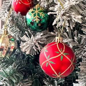 Detailed view of red, green and gold Christmas balls with gold glitter snowflakes