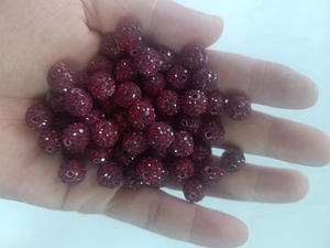 Detailed view of 10mm dark red clay shamballa beads held in palm for size scale