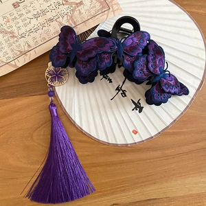 Dettaglio del fermaglio per capelli a farfalla ricamata viola con nappe e ciondolo