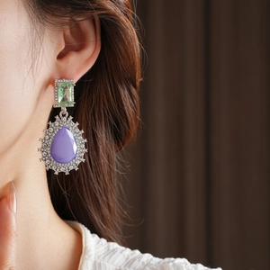 Gros plan de boucles d'oreilles vintage avec pierres violettes et détails verts sur mannequin
