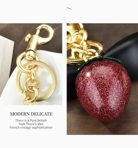 Macro detail of red glitter strawberry pendant with golden lobster clasp and chain