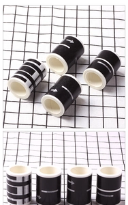 Detail of four rolls of black road traffic washi tape with white markers on grid background