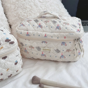 Macro shot of quilted makeup bag with elephant print, double zipper, and top handle