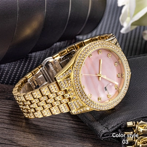 Close-up of luxury gold iced-out watch with pink marble dial and date window detail