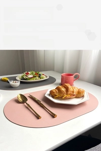 Close-up of pink and grey oval faux leather placemats with lychee texture in a dining setting