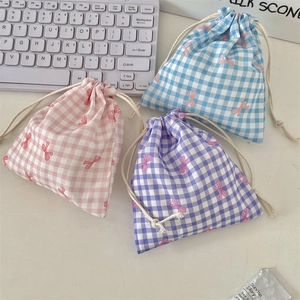 Detailed view of drawstring fabric pouches with checkered patterns and red bow prints