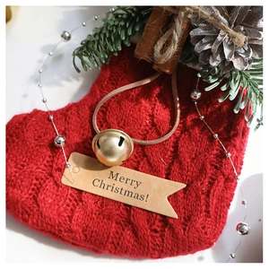 Detail of red knitted Christmas stocking with golden bell and Merry Christmas tag