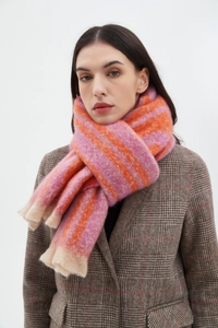 Detail of pink and orange striped scarf with beige fringes worn on a plaid blazer