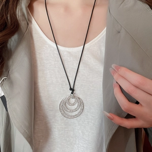 Detail of multi-layer sparkling crystal concentric circle pendant on a black cord
