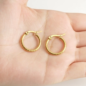 Close-up of hand holding golden spiral hoop earrings in 18k gold plated stainless steel