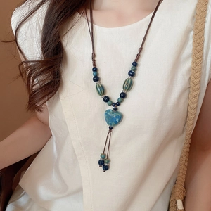 Détail macro d'un pendentif coeur en céramique bleue sur un collier tressé style ethnique